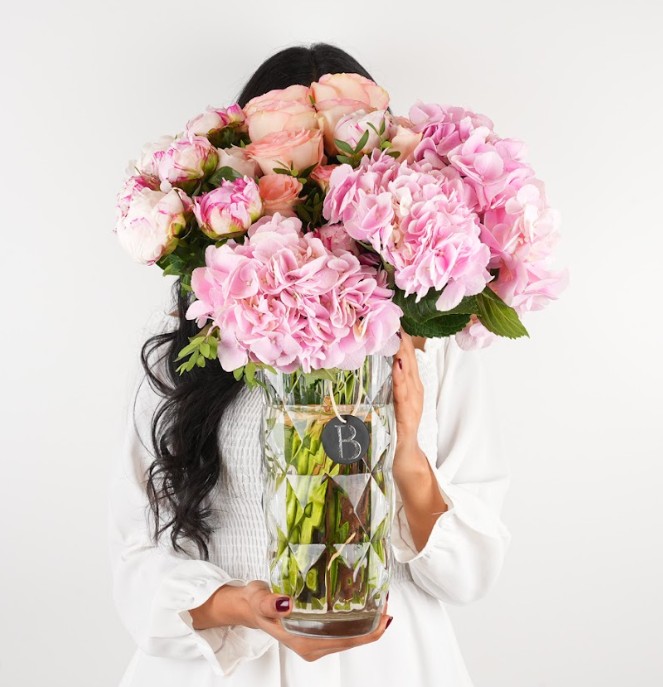 A person holding out a flower bouquet